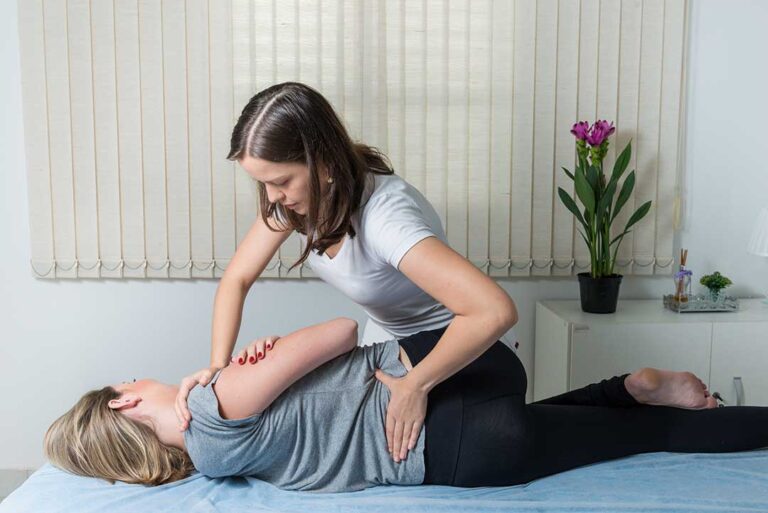 Person discussing shoulder and back pain with a clinician during a musculoskeletal examination.